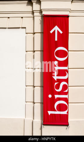A red bistro sign with an arrow hangs on a wall. Stock Photo