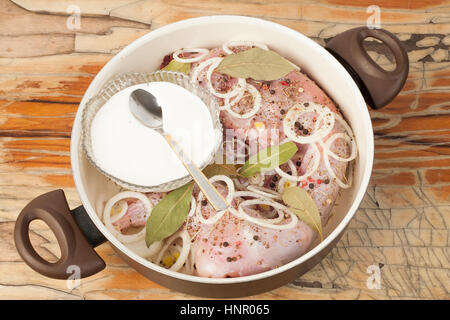 raw rabbit on a wooden Board with ingredients for stewing onion,  bay leaf, rosemary and suer cream on a wooden background - top view Stock Photo