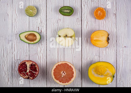 Halves of different tropical fruits placed on a white wooden board in rows Stock Photo