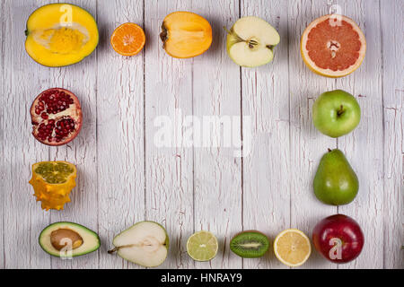 Tropical fruits cut in halves making a shape of square or rectangle placed on a white wooden table Stock Photo