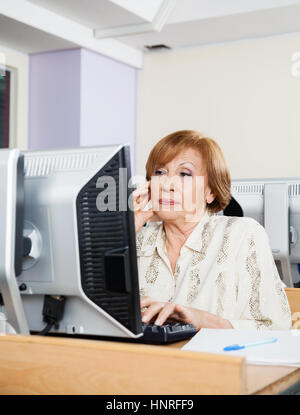 Concentrated Senior Student Using Computer In Classroom Stock Photo