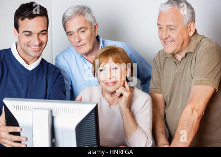 Teacher Assisting Senior People In Using Computer At Class Stock Photo