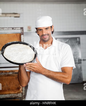 https://l450v.alamy.com/450v/hnrfhk/baker-smiling-while-showing-dough-tray-hnrfhk.jpg