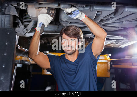 Mechanic Working Under Lifted Car At Garage Stock Photo