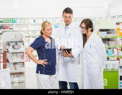 Assistant Using Digital Tablet With Pharmacists Stock Photo
