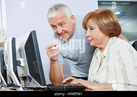 Senior Man Assisting Woman In Computer Class Stock Photo