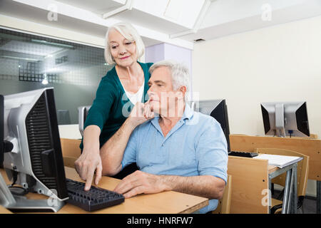 Woman Helping Male Classmate In Computer Lab Stock Photo
