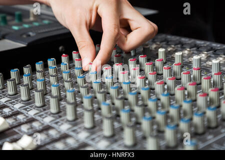 Man's Hand Turning Buttons Of Audio Mixer Stock Photo