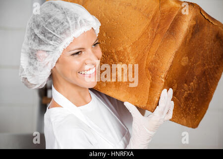 Closeup Of Baker Smiling While Carrying Big Bread Loaf