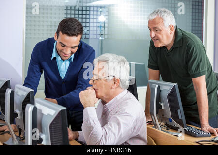 Happy Instructor Explaining Senior Men In Computer Class Stock Photo