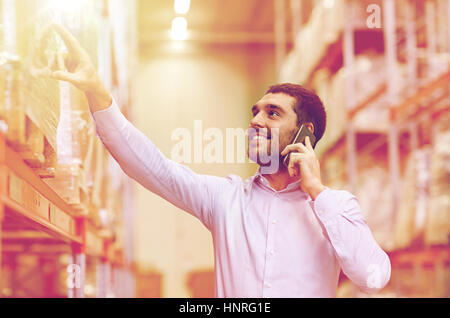 wholesale, logistic, business, export and people concept - smiling businessman calling on smartphone at warehouse Stock Photo