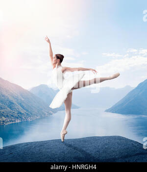 Grace ballerina keep the rack in studio, lake and mountains on background Stock Photo
