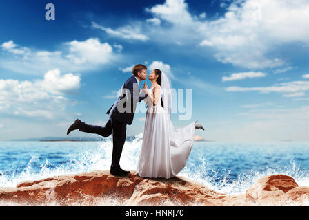 Bride and groom kissing on the sea shore. Romantic honeymoon Stock Photo
