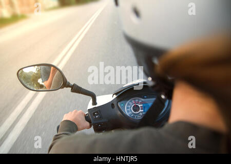 Female riding a motorcycle, motorbike, scooter on empty road. Long exposure image - high speed simulation - subjective, first person point of view Stock Photo