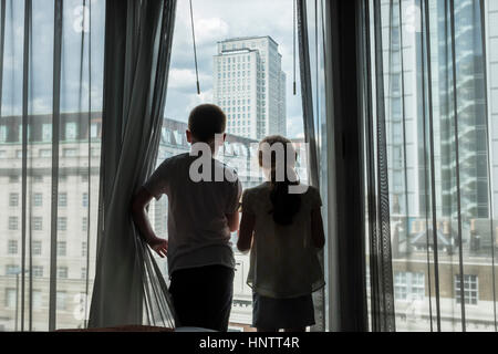 A boy and girl looking through a high window in a city. Stock Photo