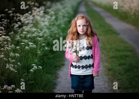 A little girl picking flowers in the countryside. Stock Photo