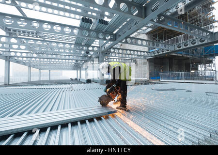 Workman cutting steel flooring on a building site in full protective clothing Stock Photo