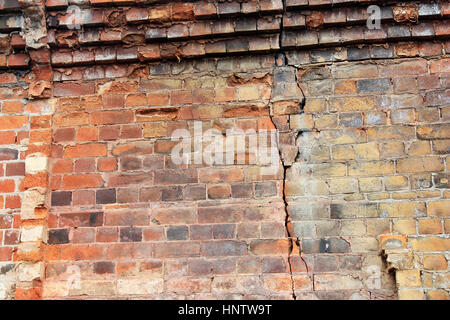Close-up view of cracked old building brick wall with eroded bricks on top, background concept Stock Photo