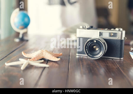 globe, camera, map, and starfish figurine on wooden table for use as traveling concept (vintage tone and selected focus) Stock Photo