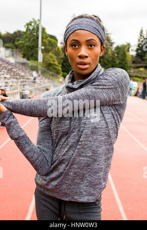 Serious Black athlete stretching arms on track Stock Photo