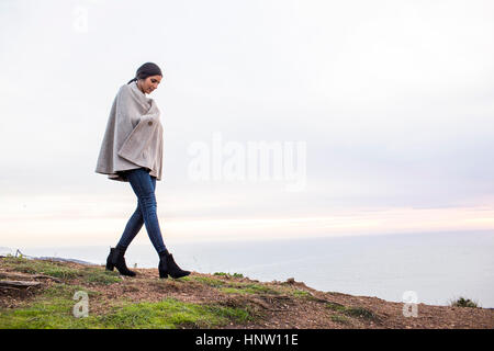 Indian woman wearing poncho walking on hill Stock Photo