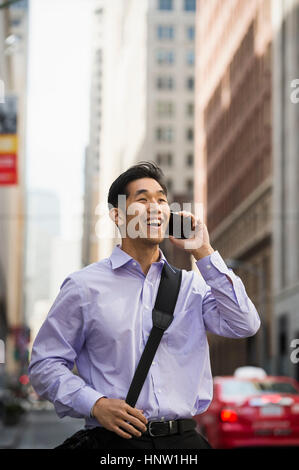 Chinese businessman talking on cell phone in city Stock Photo