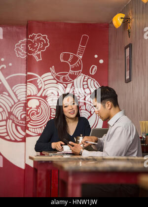 Chinese business people texting on cell phone in restaurant Stock Photo