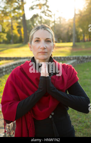 Portrait of Caucasian woman meditating in park Stock Photo