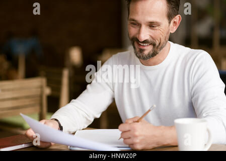Delighted bearded man making notes in the cafe Stock Photo