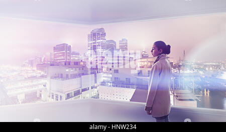 Mixed Race girl admiring cityscape from window Stock Photo