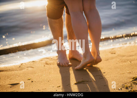 Legs of couple hugging at beach Stock Photo