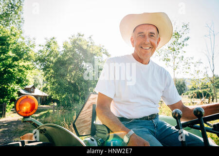 Caucasian farmer sitting on tractor Stock Photo