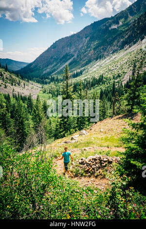 Caucasian woman hiking downhill on path in mountains Stock Photo