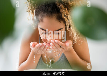 Mixed Race woman splashing water on face Stock Photo