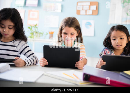 Girls using digital tablets in classroom Stock Photo