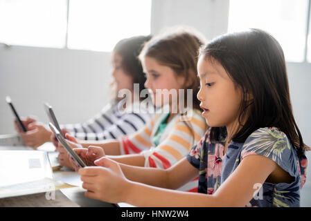 Girls using digital tablets in classroom Stock Photo