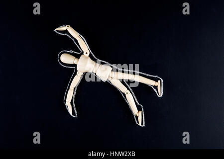 Wooden dummy figurine laying on the floor with chalk outline - crime or suicide concept Stock Photo