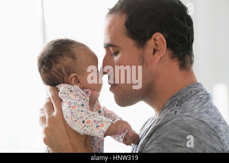 Hispanic father rubbing noses with baby daughter Stock Photo