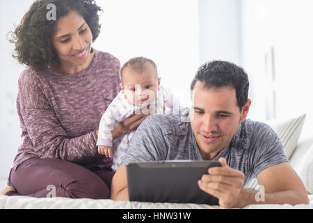 Hispanic mother and father with baby daughter watching digital tablet Stock Photo