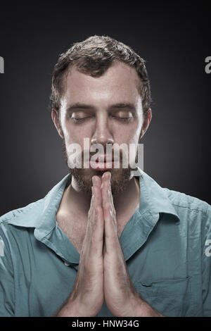 Serious man praying with eyes closed Stock Photo