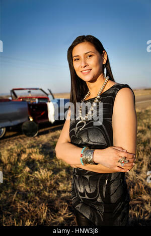 Portrait of smiling woman standing in grass near car Stock Photo