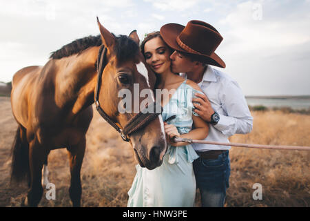 Caucasian cowboy kissing woman on cheek near horse Stock Photo