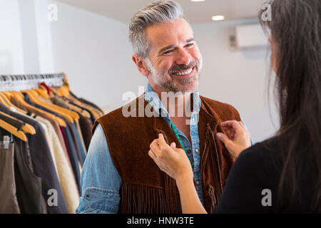 Woman helping man with fringe vest in store Stock Photo