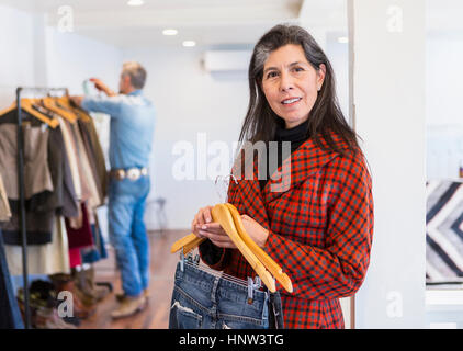Woman shopping for jeans in clothing store Stock Photo