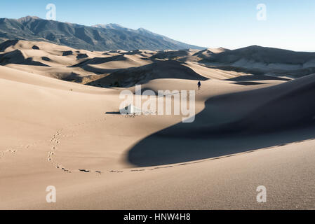 Footprints of camper walking near tent in sand dunes Stock Photo