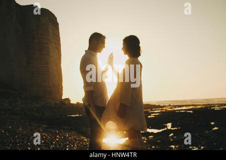 Caucasian couple pressing hands on beach at sunset Stock Photo