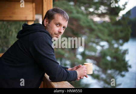 Caucasian man leaning on railing drinking coffee Stock Photo