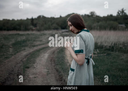 Pensive Caucasian woman standing near dirt road Stock Photo