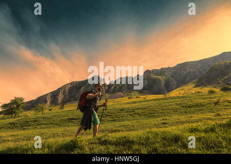 Young man with nordic sticks hiking at dusk in Apuseni Mountains in Transylvania,Romania. Stock Photo