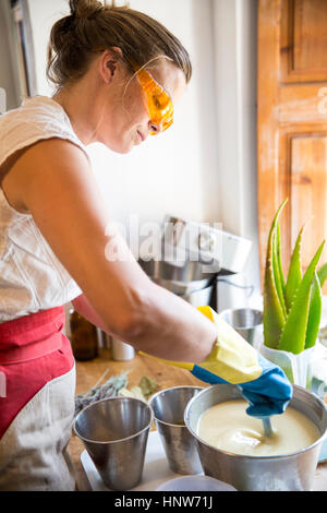 Mid section of woman stirring bowl of liquid lavender soap in handmade soap workshop Stock Photo